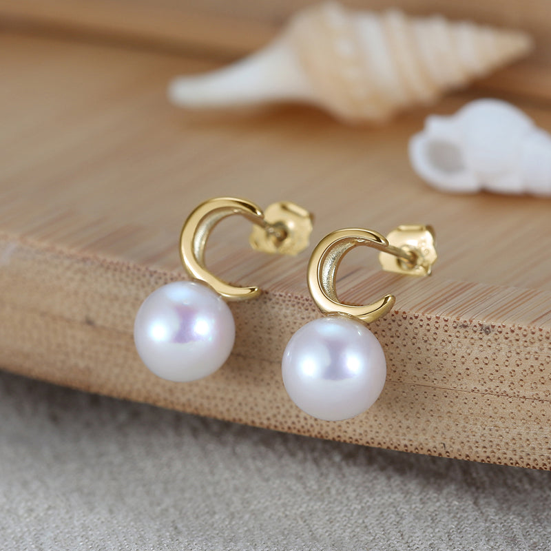 Pearl earrings with gold vermeil moon shape on a wooden surface