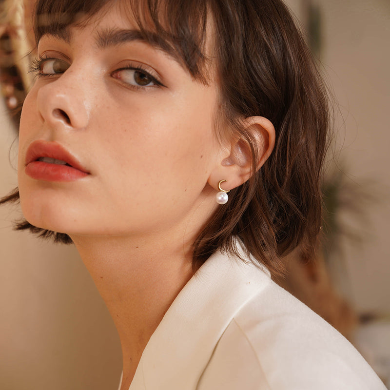 Close-up of a woman wearing pearl earrings with a blurred background