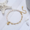 Pearl bracelet with a gold heart charm on a white background