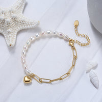 Pearl bracelet with a gold heart charm on a white background