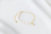 Pearl bracelet with a gold heart charm on a white background