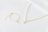 Pearl bracelet  and matching necklace with a gold heart charm on a white background