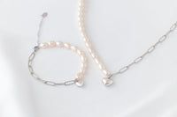 Pearl bracelet and matching necklace with a silver heart charm on a white background