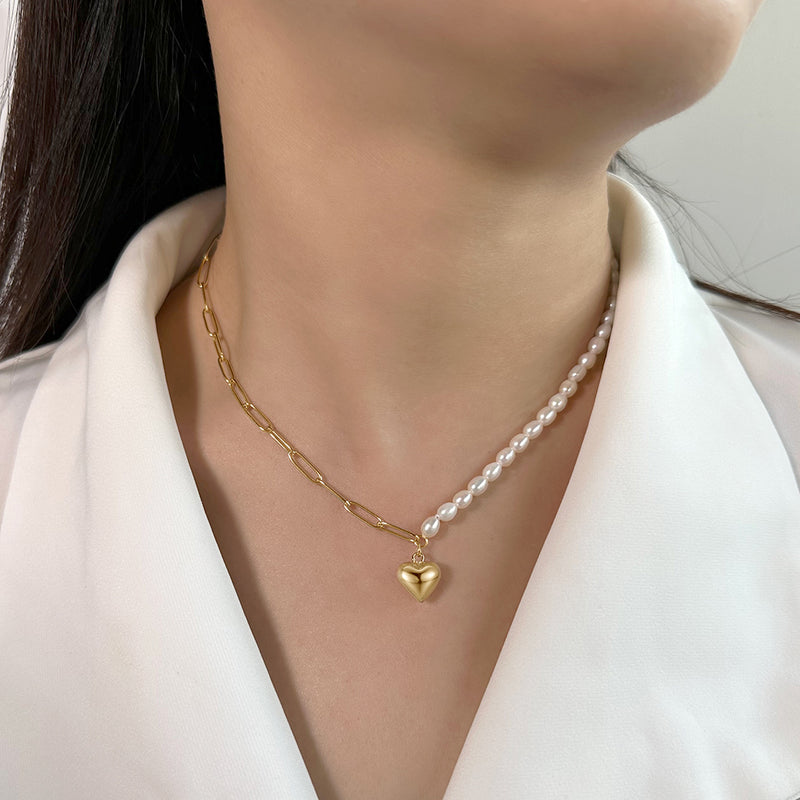 Gold chain necklace with a heart pendant and pearl necklace on a person 