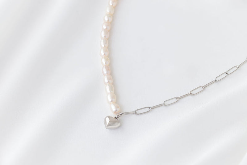Pearl necklace silver with a gold heart pendant on a white background 