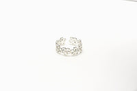 A silver ring with a polished finish, featuring a delicate design of joined flowers on a white background