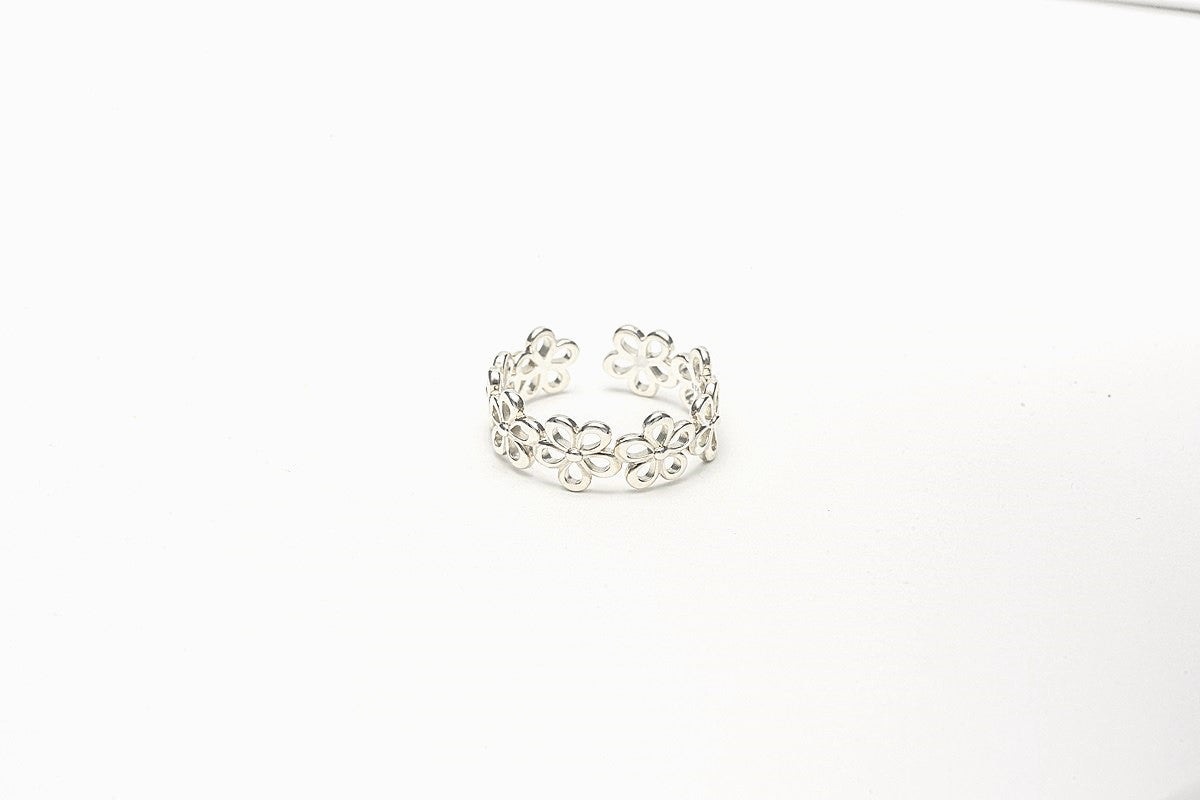A silver ring with a polished finish, featuring a delicate design of joined flowers on a white background