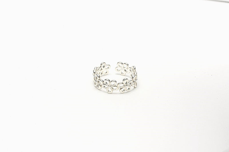 A silver ring with a polished finish, featuring a delicate design of joined flowers on a white background
