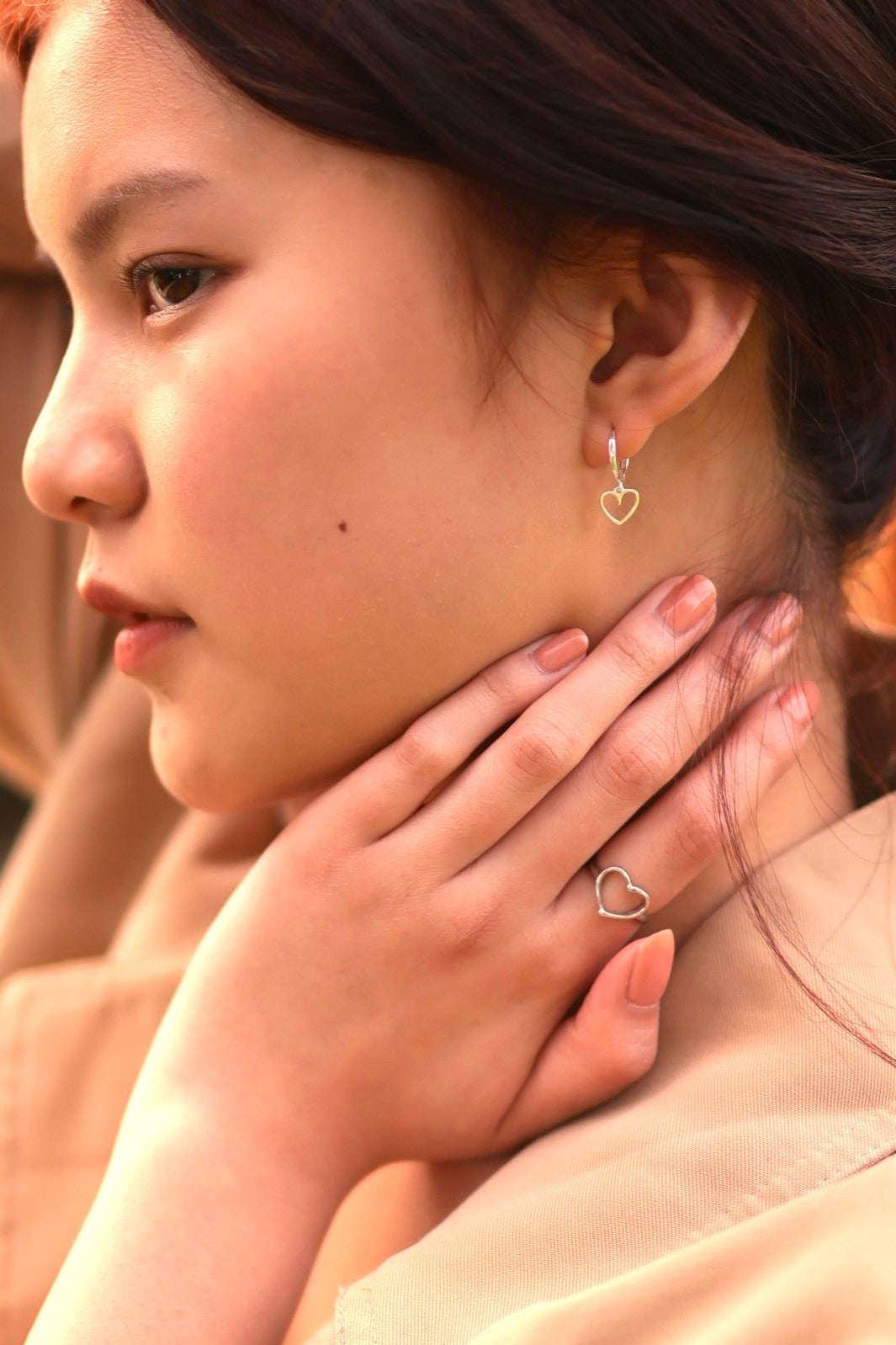 Close-up of a person wearing heart-shaped earrings and a ring.