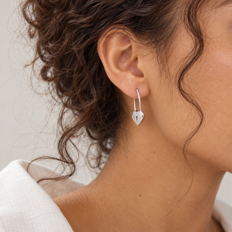 woman wearing sterling silver heartshape with a lock dangle earrings