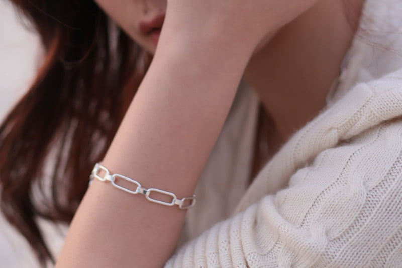 A close up of a woman wearing a chain design silver bracelet