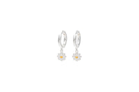 A pair of sterling silver huggie earrings with a single daisy design on a white background.