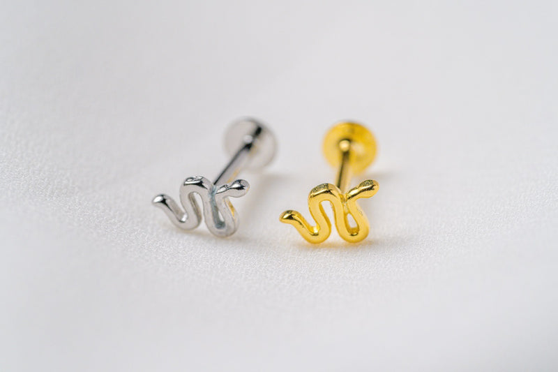 A silver and a gold shaped earring on a white background