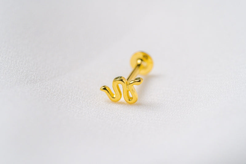 A gold snake shaped earring on a white background.