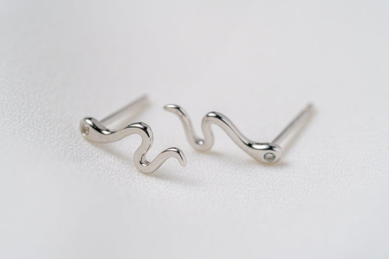 A pair of silver stud earrings with a snake-like pattern, displayed against a white background.