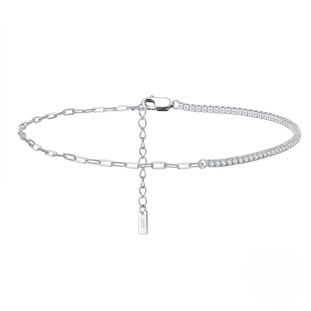 A silver anklet with a chain design and a small tag attached to it, displayed against a white background.