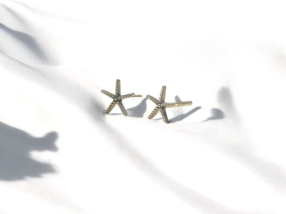 A pair of sterling silver stud earrings with a starfish design on a white background.