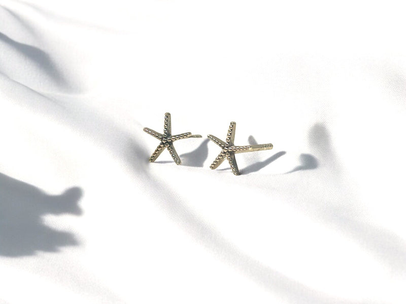 A pair of sterling silver stud earrings with a starfish design on a white background.