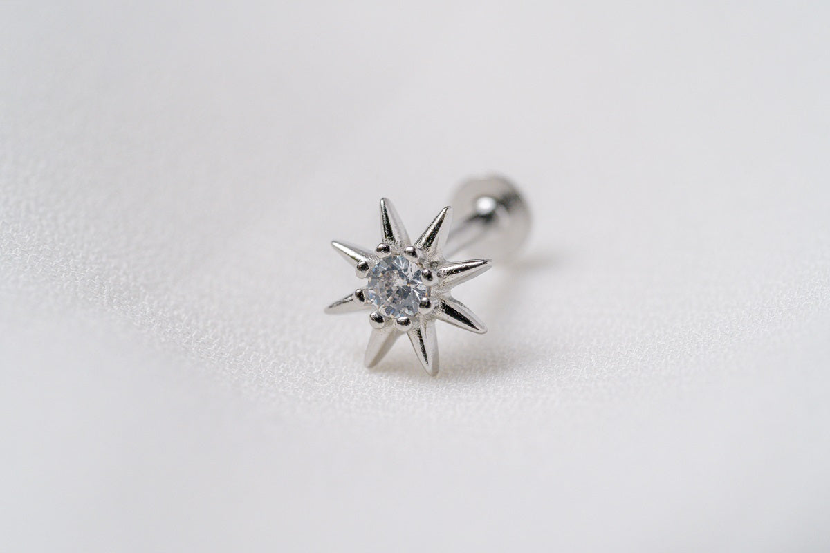 One silver star shaped earring with a cubic zirconia in the centre on a white background