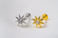 One silver and one gold star shaped earring with a cubic zirconia in the centre on a white background