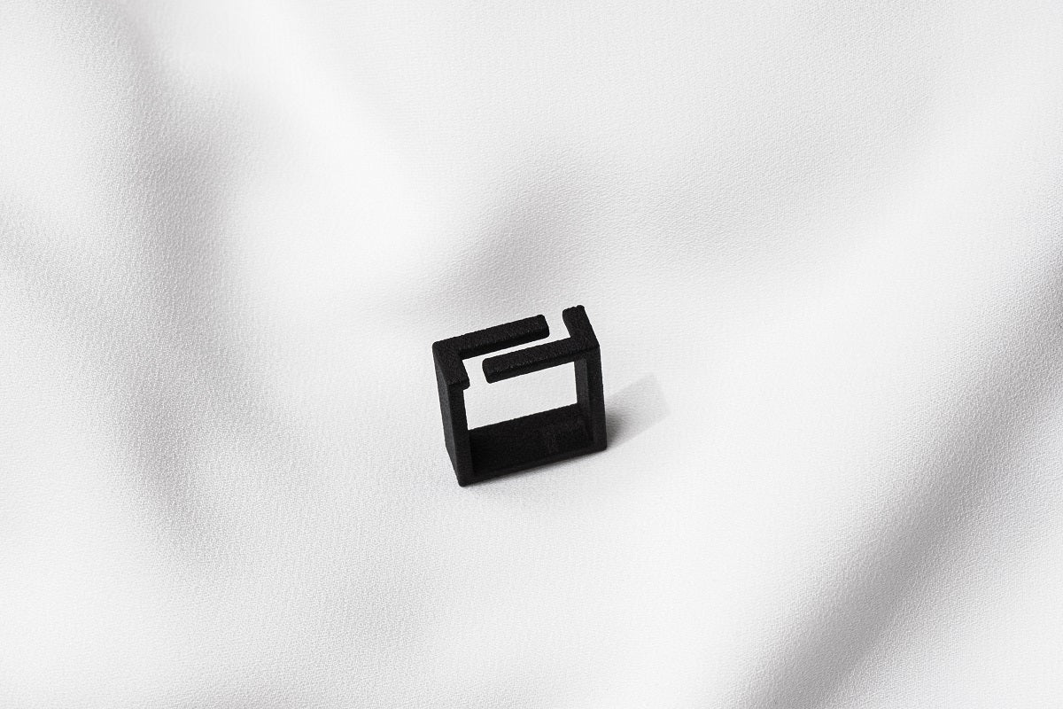 A matte black ring with a minimalist design, placed on a white textured surface.