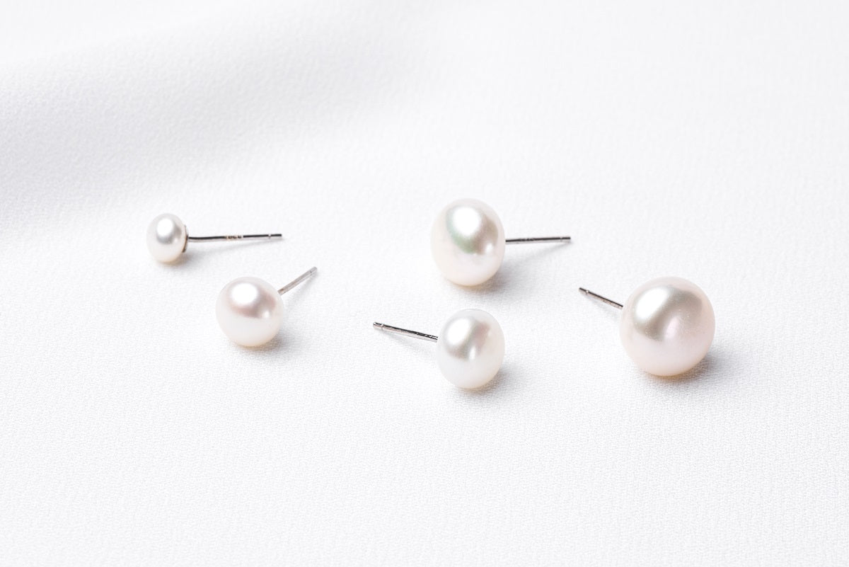A series of pearl button stud earrings in various sizes on a white background.