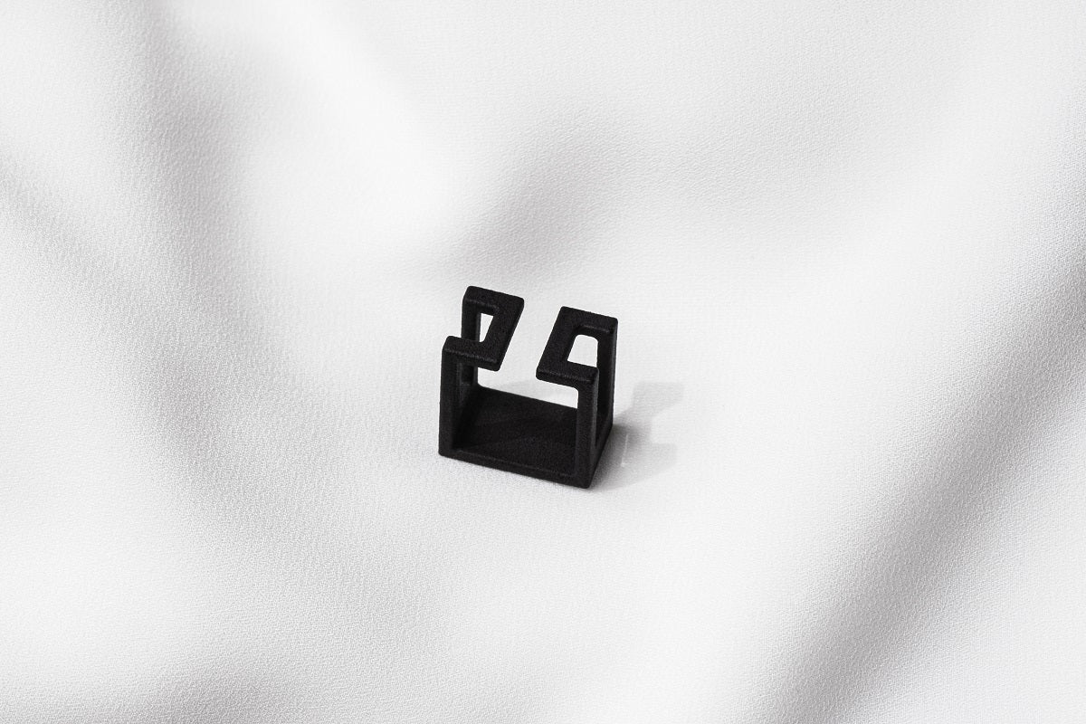 A matte black ring with a minimalist design, placed on a white textured surface.