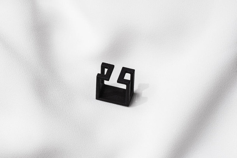 A matte black ring with a minimalist design, placed on a white textured surface.