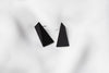A pair of matte black, triangular earrings on a white background.