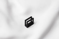 A matte black ring with a minimalist design, placed on a white textured surface.