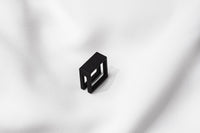 A matte black ring with a minimalist design, placed on a white textured surface.