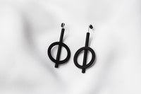 A pair of matte black earrings with a minimalist design, consisting of two overlapping circles on a white background.