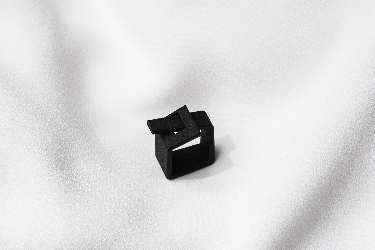 A matte black ring with a minimalist design, 3D printed from sustainable PA12 nylon, displayed on a white background.
