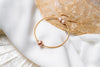 A gold and rose pearl bracelet on a white and seashell background