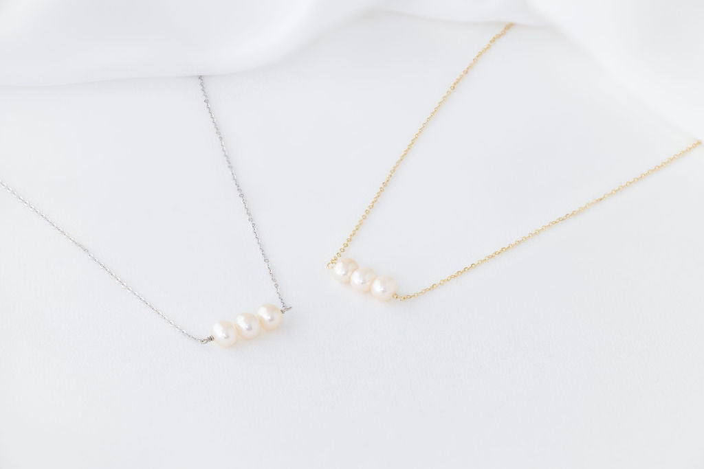 Two pearl necklaces with gold and silver chains, featuring three white baroque-shaped pearls each, displayed against a white background.