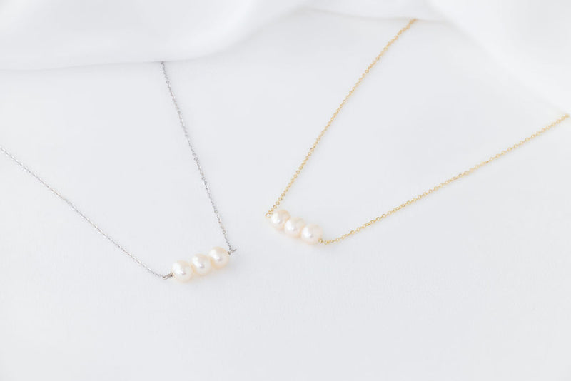 Two pearl necklaces with gold and silver chains, featuring three white baroque-shaped pearls each, displayed against a white background.