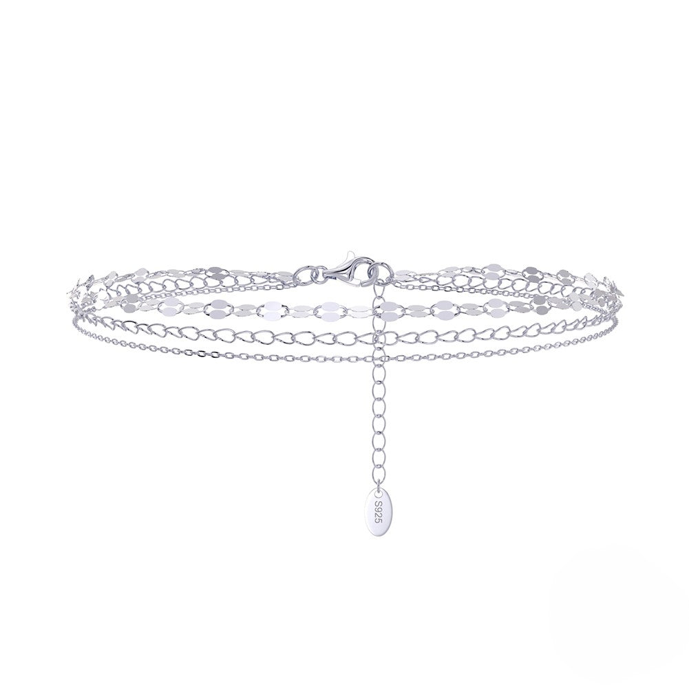 A silver anklet with 3 bands ona  white background