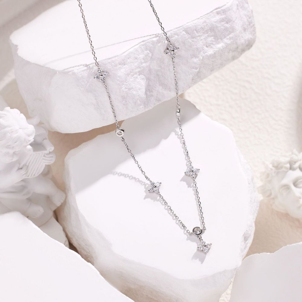 Troika necklace layed out on the white background featuring silver pendants with cubic zirconias