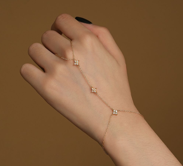 A close up of a womans hand weaing a full hand bracelet in gold featuring cubic zirconias in a star pattern