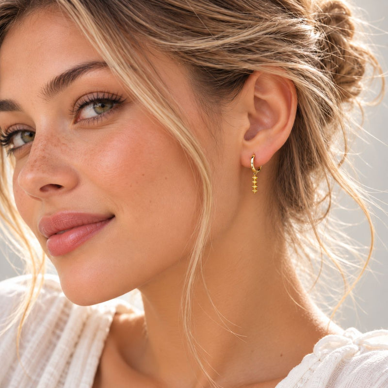 model wearing popular yellow on gold dangle jewel huggies