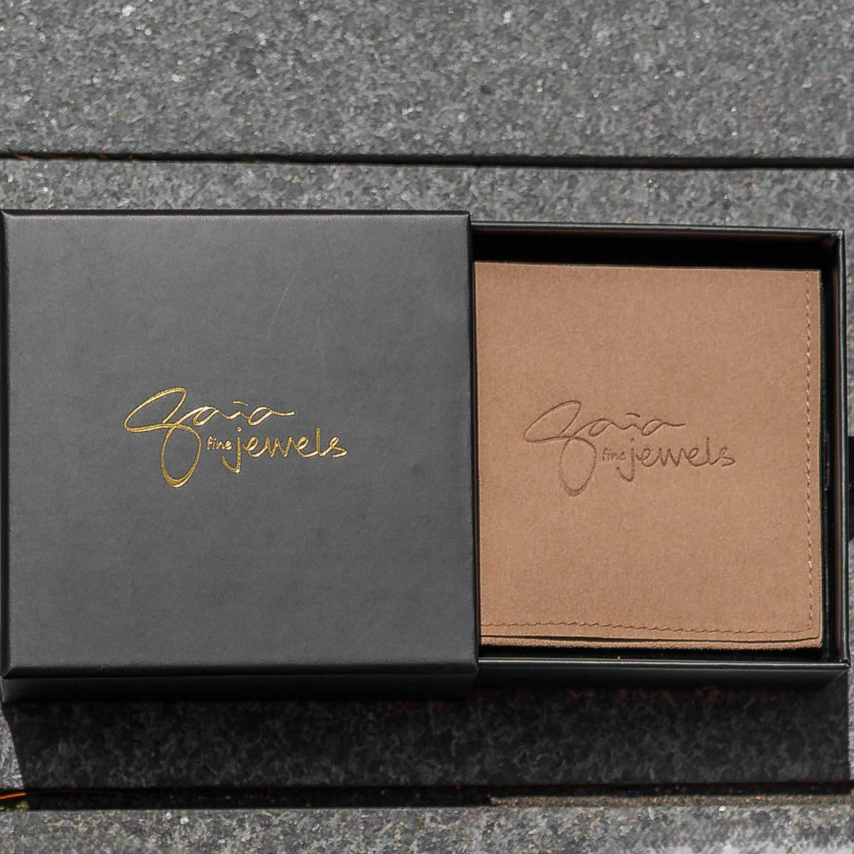 Black and brown jewelry box with branding on a gray surface