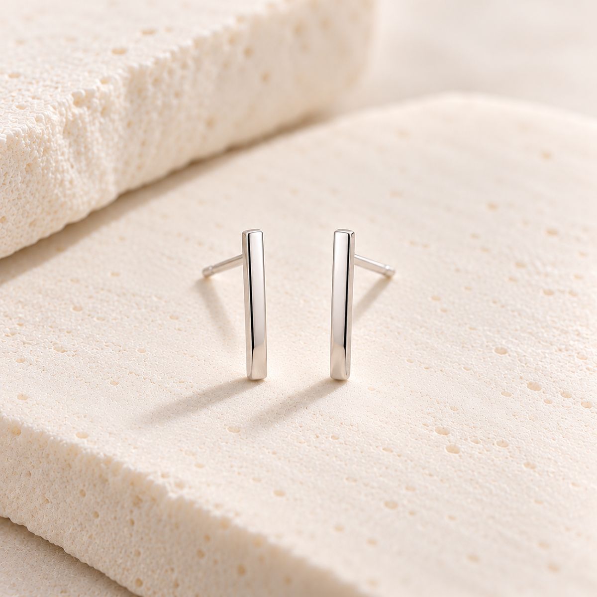 minimal sterling silver bar stud earrings on a stone background 