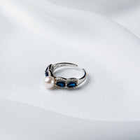An adjustable size ring with a polished finish, made of sterling silver and blue cubic zirconia, featuring a white freshwater pearl.