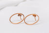 Two rose gold circle shaped earrings on a white background