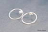 Two silver circle shaped earrings on a white background