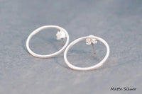 Two silver circle shaped earrings on a white background