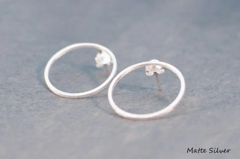 Two silver circle shaped earrings on a white background