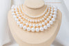 A white pearl choker necklace with a sterling silver chain, displayed on a necklace display stand