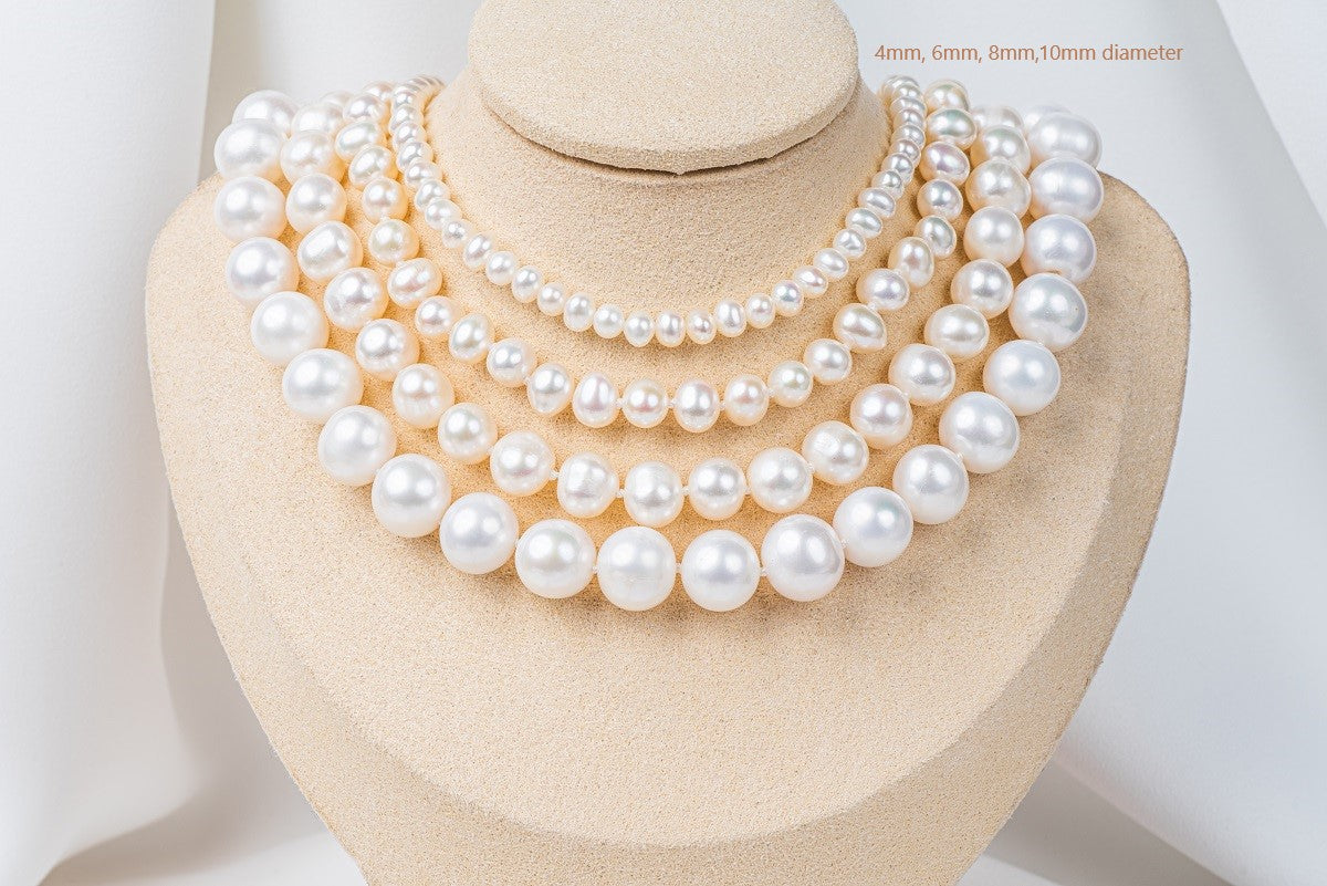 A white pearl choker necklace with a sterling silver chain, displayed on a necklace display stand