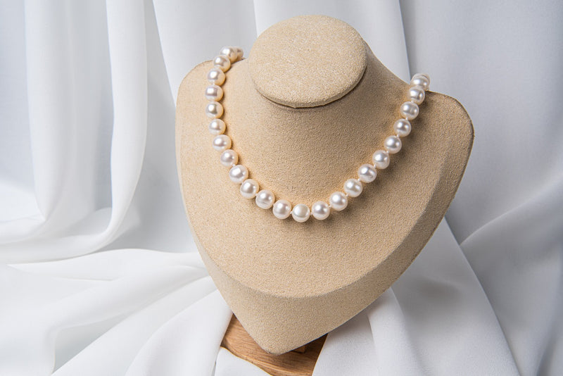 A white 10 mm pearl choker necklace with a sterling silver chain, displayed on a necklace display stand